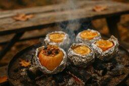 Two halved apples filled with granola and baked over an open campfire.