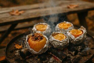 Two halved apples filled with granola and baked over an open campfire.