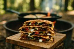 Golden brown quesadilla wedges filled with roasted vegetables and melted goat cheese on a rustic plate.