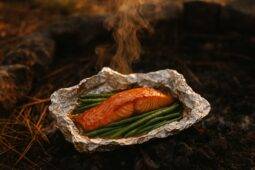 Salmon fillet and green beans coated in maple Dijon sauce wrapped in foil ready for grilling.