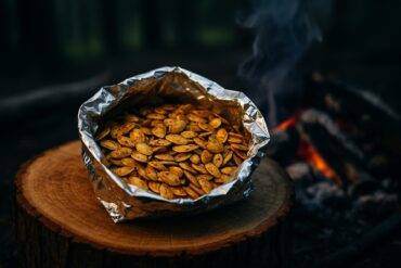 Spiced pumpkin seeds inside a foil packet ready for cooking over a campfire.