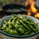 Edamame pods tossed with garlic and herbs roasting on a campfire grill.