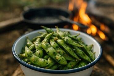 Edamame pods tossed with garlic and herbs roasting on a campfire grill.