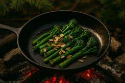 Broccolini charred in a skillet topped with toasted almonds ready to serve.