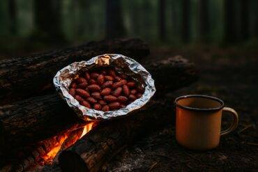 Close-up of roasted almonds coated in a smoky BBQ seasoning in a camping pot.